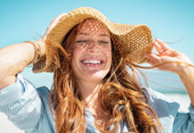 Frau mit Sonnenhut genießt den Sommer - Hautprobleme im Sommer