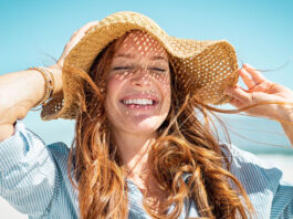 Frau mit Sonnenhut genießt den Sommer - Hautprobleme im Sommer