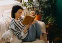 Frau sitzt auf der Couch und liest Feminismus-Bücher