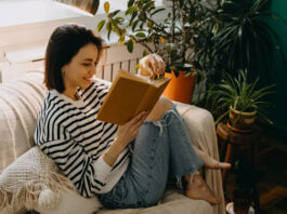 Frau sitzt auf der Couch und liest Feminismus-Bücher
