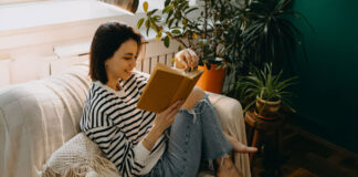 Frau sitzt auf der Couch und liest Feminismus-Bücher