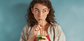 Frau trinkt einen grünen Smoothie aus einem Strohhalm mit Proteinpulver von HANS Brainfood