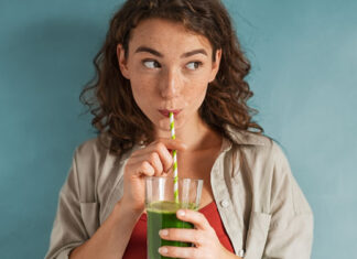 Frau trinkt einen grünen Smoothie aus einem Strohhalm mit Proteinpulver von HANS Brainfood