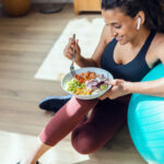 Frau mit Gymnastikball und Bowl pflegt einen gesunden Lebensstil