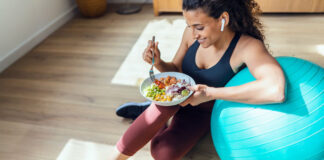 Frau mit Gymnastikball und Bowl pflegt einen gesunden Lebensstil