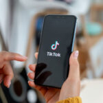Frau hält Smartphone mit TikTok in der Hand