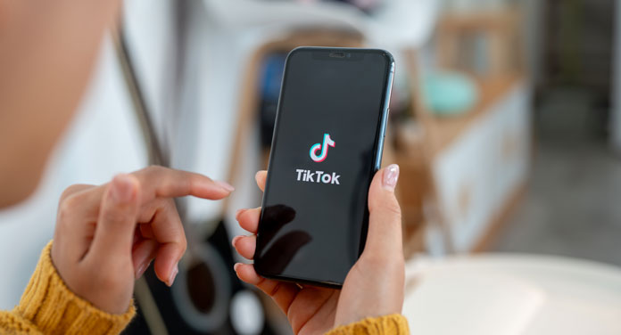 Frau hält Smartphone mit TikTok in der Hand