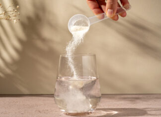 Kollagen Nahrungsergänzungsmittel Pulver wird in ein Wasserglas gegeben