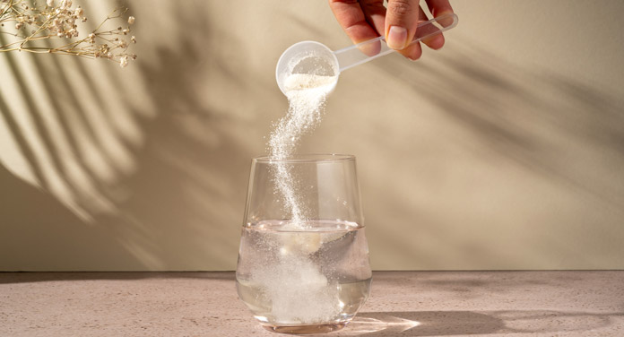 Kollagen Nahrungsergänzungsmittel Pulver wird in ein Wasserglas gegeben