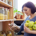 Frau steht in ihrem Vorratsschrank und schaut nach, was sie für ihre Aufbrauch-Challenge verwenden kann