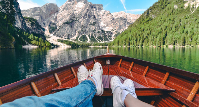 Zwei Personen sitzen im Boot und blicken auf die Bergkulisse, eine typische Szene für den Auftakt eines Reise-Fotobuch