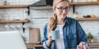 Frau arbeitet am Schreibtisch mit Taschenrechner - Psychologie des Geldes