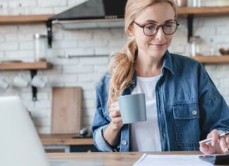 Frau arbeitet am Schreibtisch mit Taschenrechner - Psychologie des Geldes