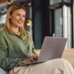 Frau arbeitet lächelnd am Laptop - selbständig machen als Frau