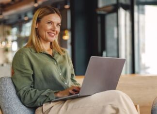 Frau arbeitet lächelnd am Laptop - selbständig machen als Frau