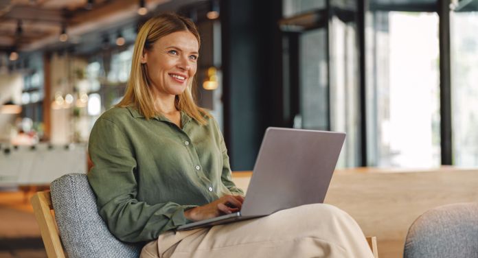 Frau arbeitet lächelnd am Laptop - selbständig machen als Frau