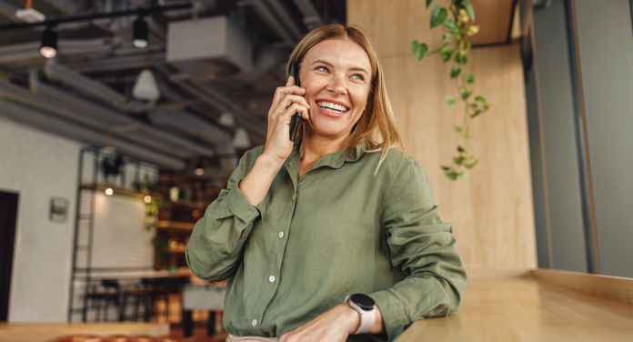 Frau spricht lächelnd am Telefon - selbstständig machen Schritt für Schritt