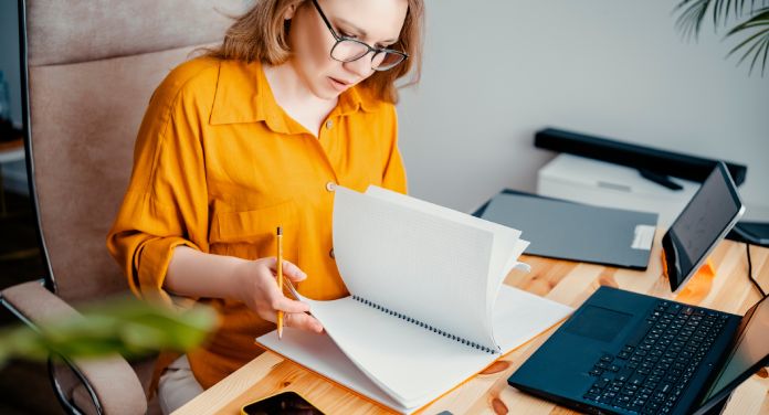 Frau arbeitet am Schreibtisch - Preise kalkulieren für Selbstständige