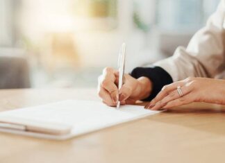 GmbH gründen als Frau: UG, GmbH oder Einzelunternehmen? Frau schreibt auf einem Dokument - GmbH gründen als Frau