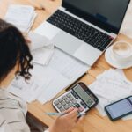 Frau arbeitet an Finanzen am Tisch - selbstständig finanziell sicher