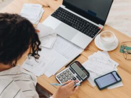Frau arbeitet an Finanzen am Tisch - selbstständig finanziell sicher