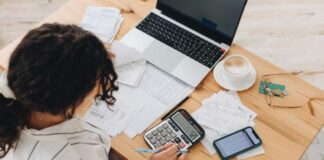 Frau arbeitet an Finanzen am Tisch - selbstständig finanziell sicher