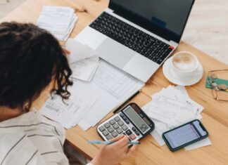Frau arbeitet an Finanzen am Tisch - selbstständig finanziell sicher