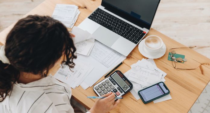 Frau arbeitet an Finanzen am Tisch - selbstständig finanziell sicher